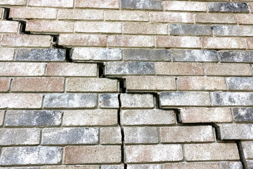 Dalinghaus Foundation Repair inspecting severe stair-step cracks in a brick foundation wall.